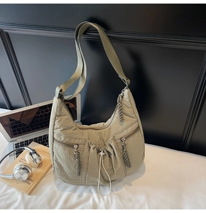 Detail view of khaki green crescent bag with pleated drawstring and woven zipper pulls