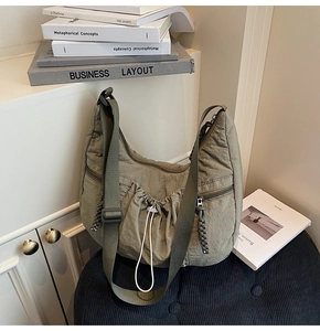 Detail of olive green crescent crossbody bag showing textured pleated nylon and drawstrings