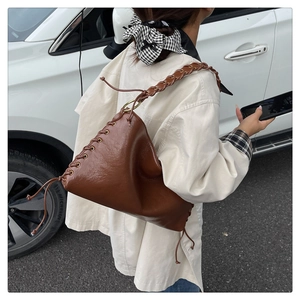 Détail du sac à main en cuir marron foncé avec cordon de serrage et bandoulière tressée