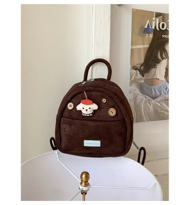 Detail view of mini brown suede backpack featuring dog embroidery and wooden buttons