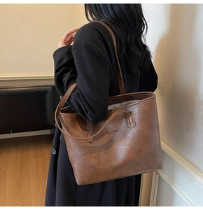 Detail showing the dark brown tote bag texture and embossed lettering on the side