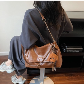 Brown retro shoulder bag with leather texture, metal chain, and cute teddy charm detail