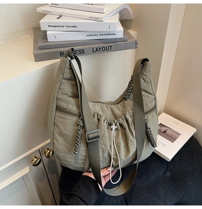 Detailed view of olive green nylon hobo bag with drawstring pleats and side zipper pockets