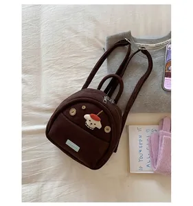 Detail view of brown faux suede mini backpack with cute cartoon patch and wood buttons