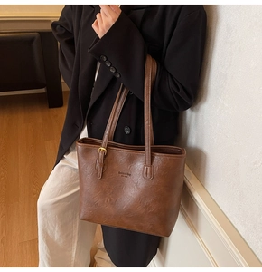 Macro detail of dark brown tote bag with premium pebbled leather texture and shoulder strap
