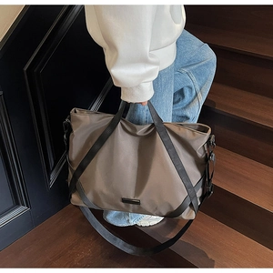 Detail der kaffeebraunen Reisetasche mit schwarzen Tragegurten und Metalldekor