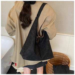 Minimalist black suede hobo bag shown on shoulder in a cozy home setting with a white tub
