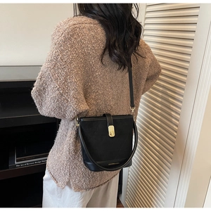 Detail of black matte bucket bag with gold twist lock and adjustable shoulder strap