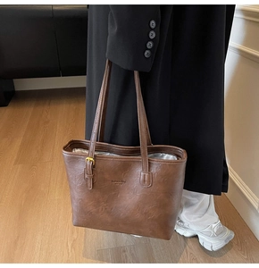 Detail of vintage brown leather tote bag with fashion bag text and gold buckle strap