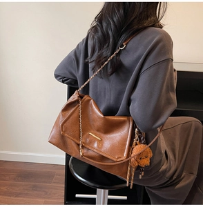 Close-up of brown vintage chain shoulder bag with cute teddy bear plush pendant