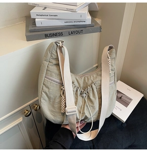 Detail of sage green ruched nylon bag featuring multiple zipper pockets and wide strap