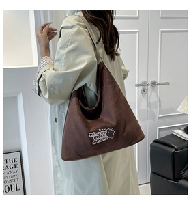 Detail of dark brown faux suede tote bag featuring cartoon embroidery on the side