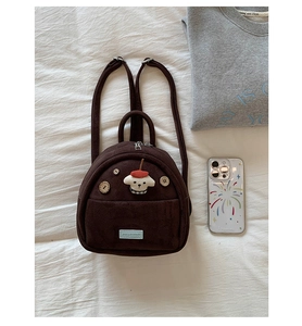 Detail of vintage brown suede mini backpack with cute dog patch and corduroy texture