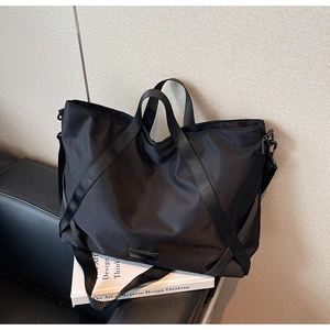 Detailaufnahme der Reisetasche aus schwarzem Nylon mit Griffen und Schultergurt