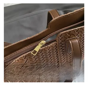 Macro shot of brown woven leather tote texture with premium gold metal zipper detail