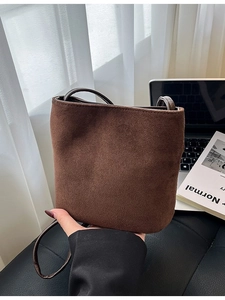 Brown faux suede bucket bag with long strap shown in a cozy indoor lifestyle setting