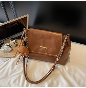Close-up of vintage brown leather underarm bag with gold chain and cute poodle charm