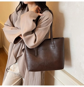 Detail of coffee brown tote bag with fashion bag NEW YORK text on matte faux leather
