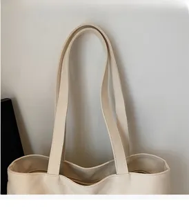 Detail of cream canvas tote bag showing wide durable handles and sturdy textured fabric