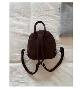 Detail of dark brown faux suede backpack showing adjustable slim straps and stitching