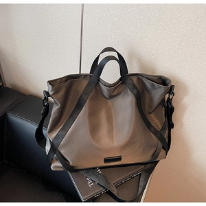 Detail der taupefarbenen wasserdichten Nylon-Reisetasche mit glatter Textur und Griffen