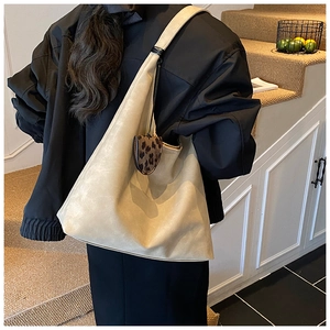 Detail of cream oversized tote bag with soft texture and leopard print charm accessory