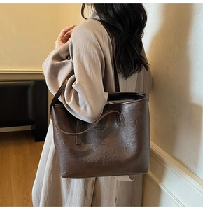 Detailed side view of a large dark brown faux leather tote bag with vintage texture