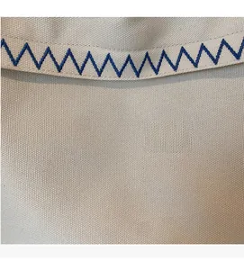 Close-up of beige canvas tote bag featuring blue wavy embroidery and premium fabric texture