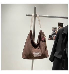 Detail of brown suede leopard hobo bag with cartoon embroidery and decorative pendants