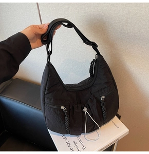 Detail of black pleated nylon half-moon crossbody bag with multi-zipper pockets