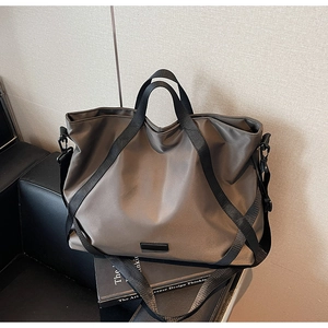 Detail der dunkelgrauen Reisetasche mit schwarzen Riemen auf Ledersofa Hintergrund