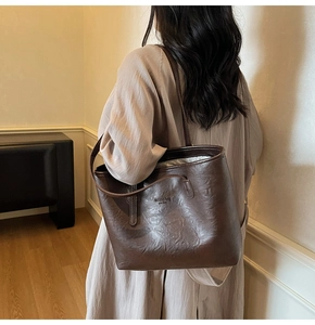 Close-up of deep brown tote bag featuring debossed New York fashion text and retro leather texture