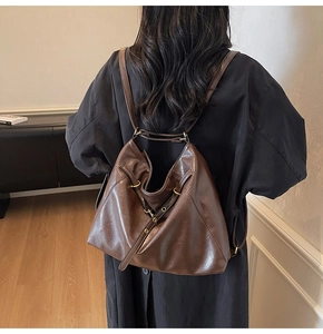 Detail view of a large brown faux leather backpack with vintage metal buckles on back