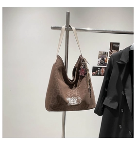 Detail of leopard print bucket bag with beige leather strap and cartoon patch embroidery