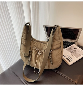 Detail view of khaki pleated dumpling bag showing drawstring pocket and wide strap