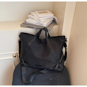 Detail einer großen schwarzen Nylontasche mit verstärkten Griffen und minimalistischem Patch