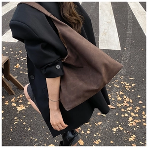 Detail of soft matte dark brown faux suede tote bag on a person in autumn street setting