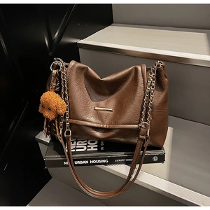 Close-up of retro dark brown pleated bag with gold metal bar and cute bear charm