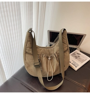 Detail of khaki pleated nylon crescent bag with adjustable wide strap and zipper pocket