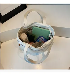 Top view of cream canvas tote bag showing spacious interior and blue wavy stitching
