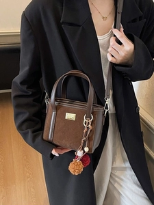 Brown faux suede crossbody bucket bag with colorful plush ball charm and gold hardware