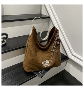 Detail of leopard print suede tote bag with bear embroidery and decorative striped ribbon