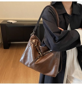 Detailed macro view of dark coffee leather texture and metal buckle on large tote bag