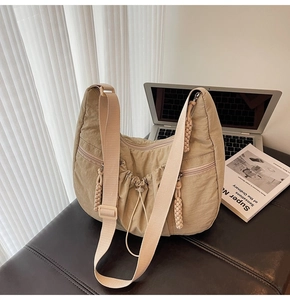 Detail of beige nylon crescent bag featuring pleated texture and braided zipper pulls