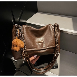Close-up of retro brown shoulder bag with metal buckle and cute plush dog pendant