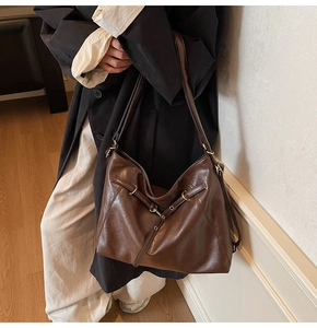 Detail of a large dark brown hobo shoulder bag with retro textured folds and buckle