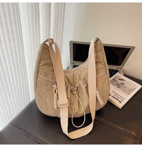 Detail of pleated nylon crescent bag with drawstring closure and wide strap