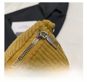 Detailed close-up of smooth silver metal zipper on yellow corduroy fanny pack