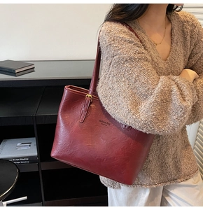 Detail of burgundy tote bag with gold buckle, leather texture and NEW YORK text