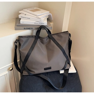 Detailansicht der khakifarbenen Nylon-Reisetasche mit schwarzen Trageriemen auf Polster